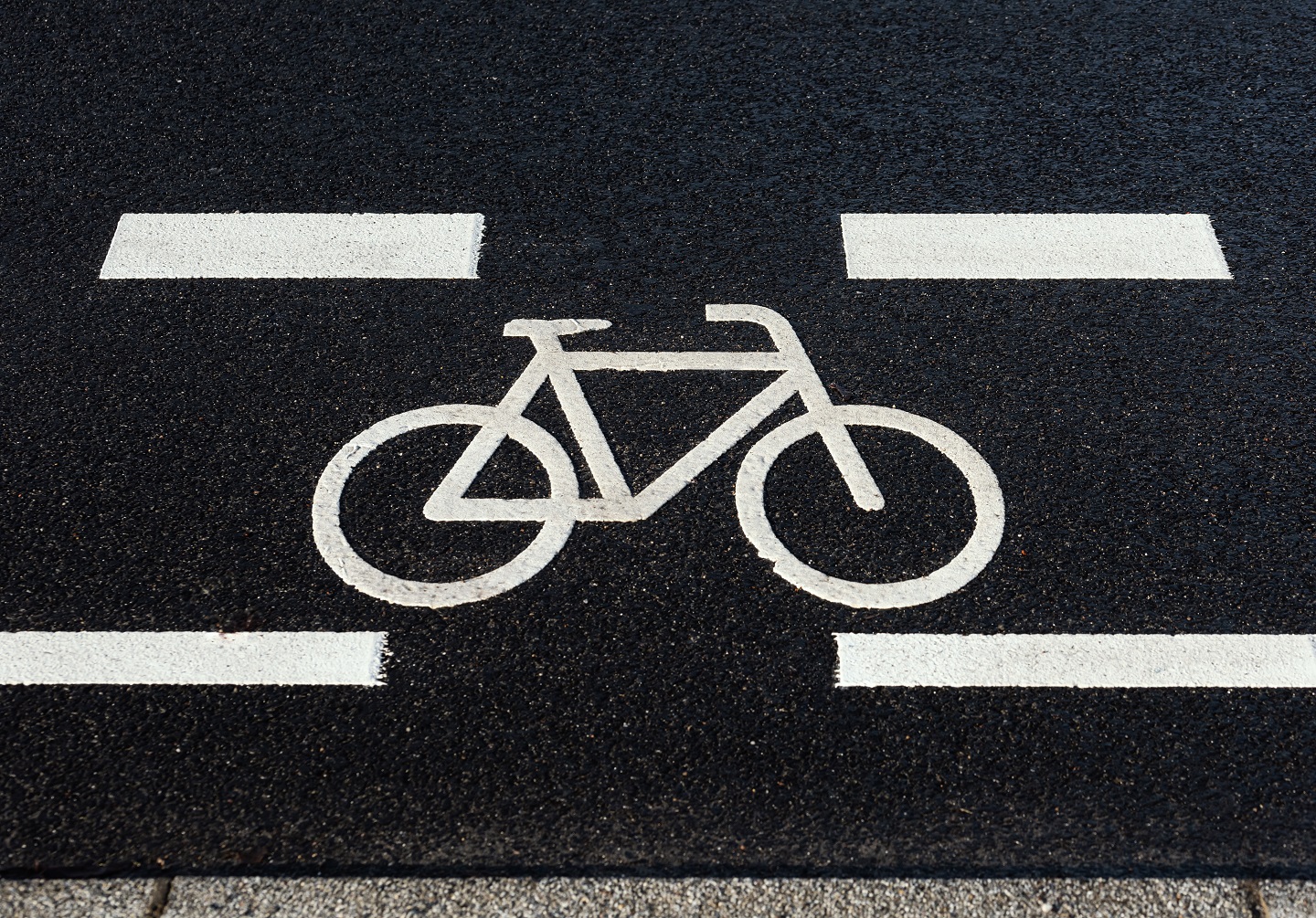 Zu sehen ist ein Fahrradsymbol aufgemalt auf einer schwarzen Straße
